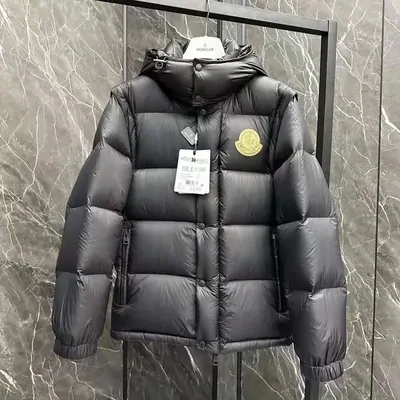 A grey quilted puffer jacket hanging on a rail against a marble wall, with its brand tag still attached