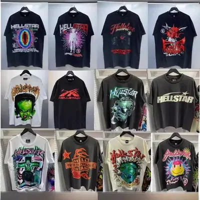 Twelve graphic t-shirts arranged against a shelf wall, printed in purple, green and red on black, grey and cream cotton